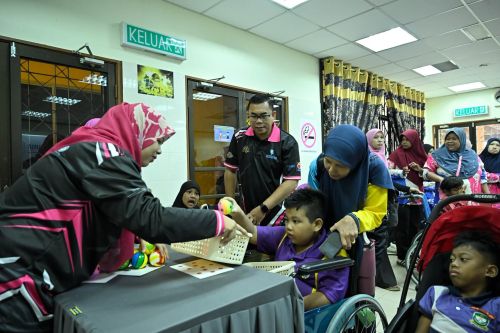 Kanak-kanak OKU bersama penjaga dan fasilitator menyertai aktiviti permainan terapeutik dalam suasana ceria dan inklusif.   
