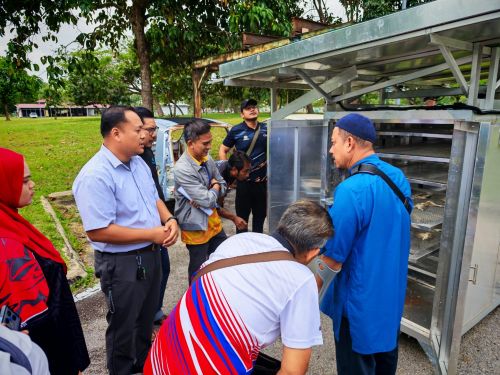 Peserta meninjau kebuk pengering hibrid dan hasil pengeringan semasa sesi amali.